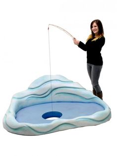 a woman standing on top of an inflatable pool with a fishing rod attached to it