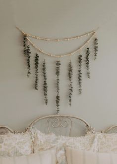 a white bed topped with lots of pillows next to a wall mounted plant on top of it