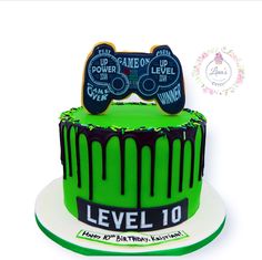 a green cake with black icing and two game controllers on top that says level 10