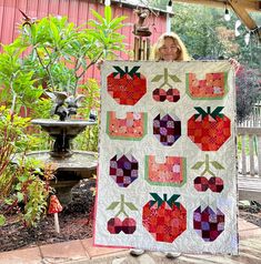 a woman holding up a quilt made with apples