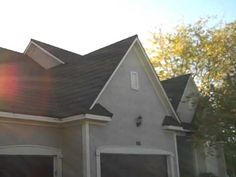 the sun shines brightly in front of a house with two garage doors and windows