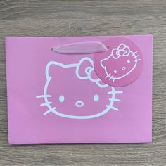 a pink hello kitty sticker on top of a piece of paper with a knife sticking out of it