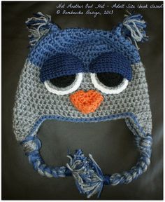 a crocheted hat with an owl's face on it, sitting on a black surface