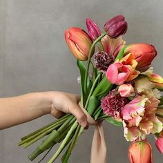 a person holding a bunch of flowers in their hands with the stems still attached to it