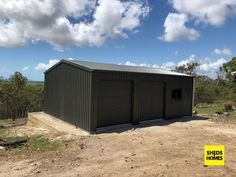 two garages on the side of a dirt road with a yellow sign in front of them