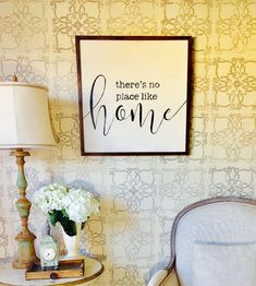 there is no place like home sign on the wall next to a chair and lamp