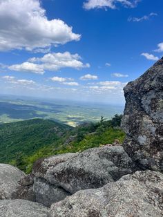 a view from the top of a mountain with rocks and grass in the foreground