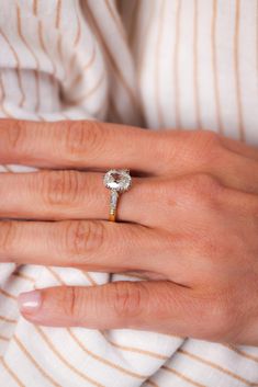 a woman's hand with an engagement ring on her left and the other hand wearing a white striped shirt