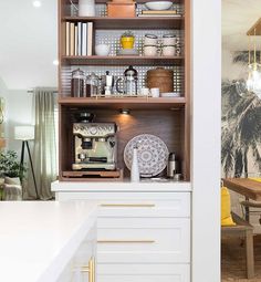 a kitchen with white counter tops and wooden shelves filled with dishes on top of them