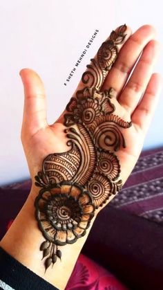 a woman's hand with henna tattoos on it