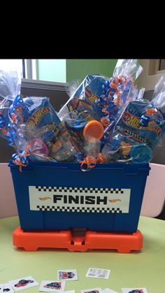 a blue bin filled with candy and candies on top of a table next to cards