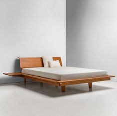 a bed that is sitting in the middle of some white flooring with a wooden headboard and foot board