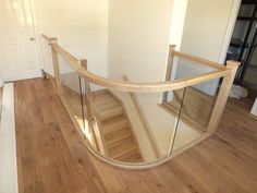 a curved glass banister with wooden handrails in an empty room next to a white door