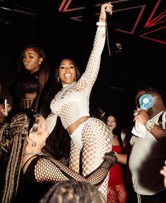 a woman in fishnet stockings dancing with other people at a club or nightclub,