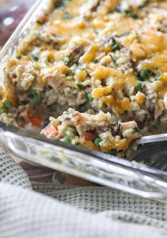 a casserole dish with chicken and vegetables in it on a tablecloth next to a fork