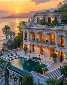 an aerial view of a mansion with a pool and ocean in the background at sunset