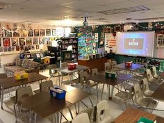 an empty classroom with desks and chairs in front of a projector screen on the wall