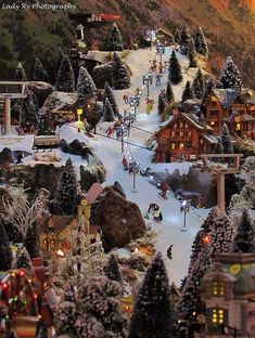 a toy town with lots of trees and lights on the top of it's mountain