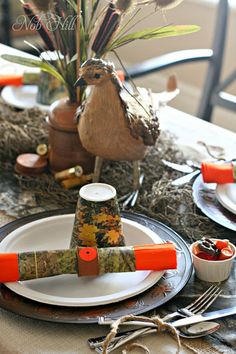 the table is set with plates, silverware and orange napkins for thanksgiving dinner