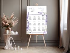 a wedding seating chart on a easel next to a table with flowers