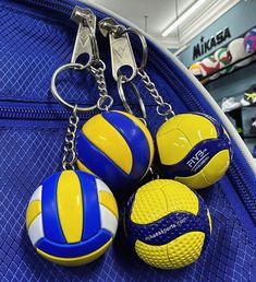 four beach ball keychains hanging on a blue mesh bag in a shoe store