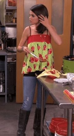 a woman standing in a kitchen with her hand on her head and holding a knife