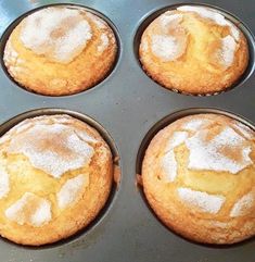 four muffins in a pan with powdered sugar on top, ready to be baked