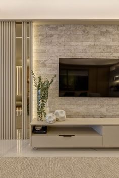 a living room with a flat screen tv mounted on the wall next to a plant