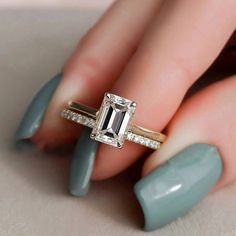 a woman's hand holding a ring with an emerald stone