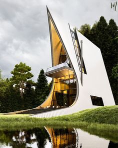 an unusual white building with a large window on it's side next to the water