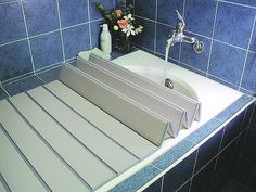 a bathroom with blue tiled walls and flooring, including a bathtub that has a shower head on the side