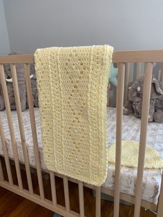 a crocheted blanket hanging from the side of a baby's crib