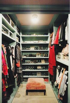 a walk in closet with lots of shoes and footwear on the shelves, along with a bench