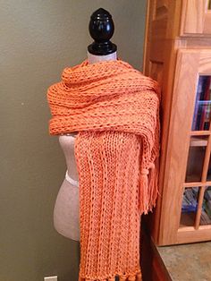 an orange knitted scarf sitting on top of a mannequin