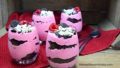 three desserts are sitting on a red place mat with spoons and fork next to them