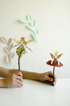 two handmade fairy figurines are held in front of a child's hand