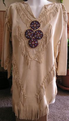 a woman's blouse with fringes and beads on the front, sitting on a mannequin