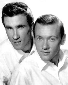 two men are posing for a black and white photo with their heads turned to the side