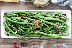 green beans with cranberries and pecans in a white serving dish on a wooden table