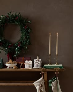 stockings hanging on a table with christmas decorations and candles in front of the fireplace mantle