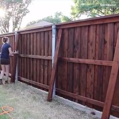 a woman standing next to a wooden fence with a ladder on it's side