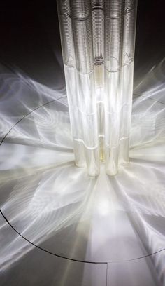 the light is shining through two tall glass vases on top of a circular table