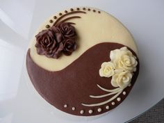 there is a chocolate cake with white frosting and flowers on the top, sitting on a plate