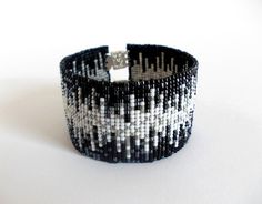 a black and white beaded bracelet with a silver ring on it's end