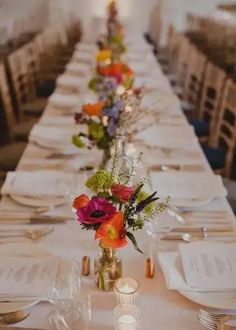 a long table is set with flowers and place settings