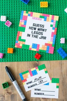 some legos are laying on top of a table with paper and markers next to them