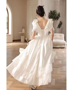 a woman in a white dress walking through a room with a chandelier hanging from the ceiling