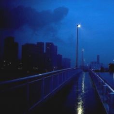 a city street at night with the lights on and dark clouds in the sky above