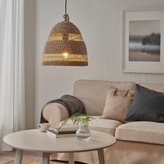 a living room filled with furniture and a lamp hanging from the ceiling over it's coffee table