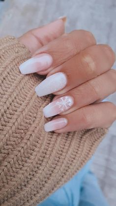 a woman's hand with white and pink nail polishes on her nails, holding a knitted hat